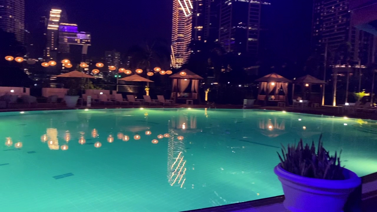 SunsetBlu illuminated pool at night with Colombo city skyline and cabana seating in the background