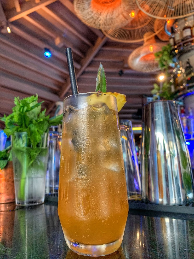 Crafted cocktail with pineapple garnish on the SunsetBlu bar counter with bokeh lighting